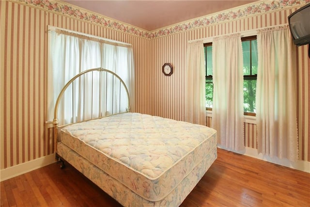 1601 Stevens Ave, Parsons, KS 67357 - bedroom featuring wallpapered walls, wood-type flooring, baseboards, and multiple windows
