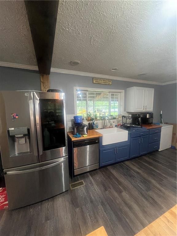 933 1300th St, Iola, KS 66749 - kitchen with appliances with stainless steel finishes, blue cabinets, a sink, dark wood-type flooring, and ornamental molding