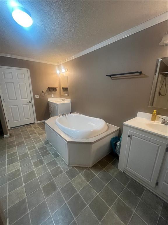 933 1300th St, Iola, KS 66749 - bathroom with ornamental molding, two vanities, a bath, tile patterned floors, and washer and clothes dryer