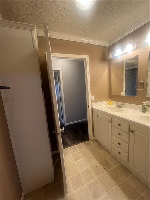 933 1300th St, Iola, KS 66749 - bathroom featuring ornamental molding, double vanity, a textured ceiling, and tile patterned flooring