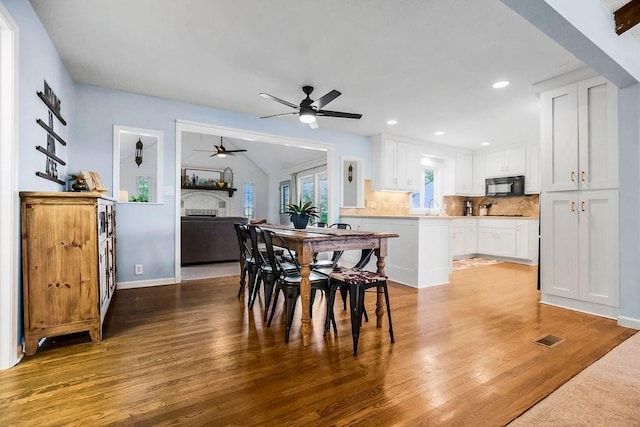 33991 Mission Belleview Rd, Louisburg, KS 66053 - dining space with wood finished floors, a fireplace, ceiling fan, recessed lighting, and lofted ceiling