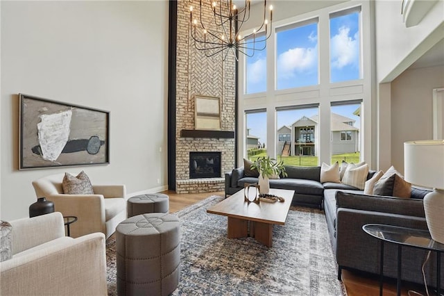 17137 Barton St, Overland Park, KS 66221 - living room featuring a high ceiling, a chandelier, wood finished floors, a fireplace, and baseboards