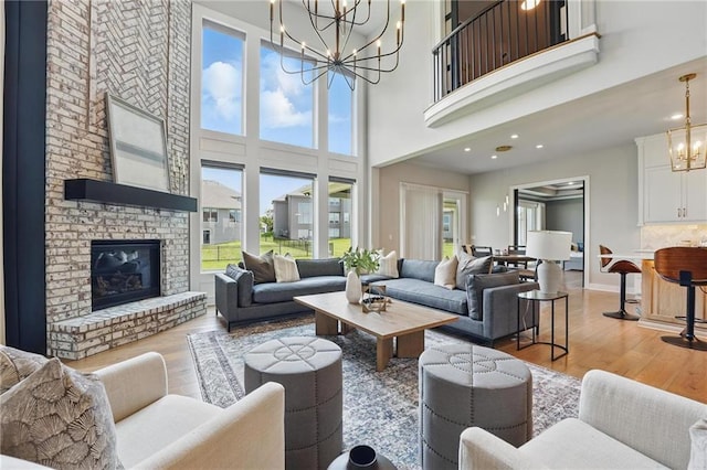 17137 Barton St, Overland Park, KS 66221 - living room with a chandelier, light wood-style flooring, a high ceiling, a brick fireplace, and recessed lighting