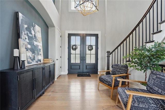 17137 Barton St, Overland Park, KS 66221 - foyer with light wood-style flooring, a chandelier, a high ceiling, stairs, and french doors