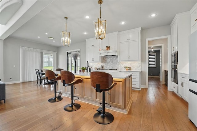 17137 Barton St, Overland Park, KS 66221 - kitchen with stainless steel appliances, a chandelier, light countertops, decorative backsplash, and a center island with sink