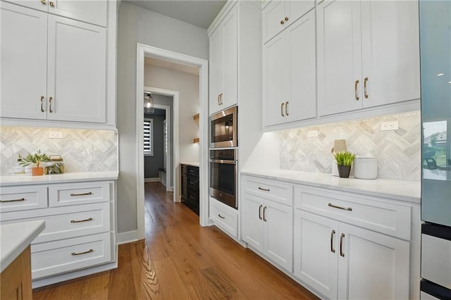 17137 Barton St, Overland Park, KS 66221 - kitchen featuring stainless steel oven, white cabinets, wood finished floors, tasteful backsplash, and baseboards