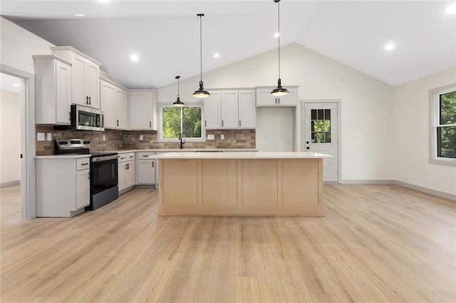 38 NW 525th Rd, Warrensburg, MO 64093 - kitchen with appliances with stainless steel finishes, vaulted ceiling, a kitchen island, light wood finished floors, and backsplash