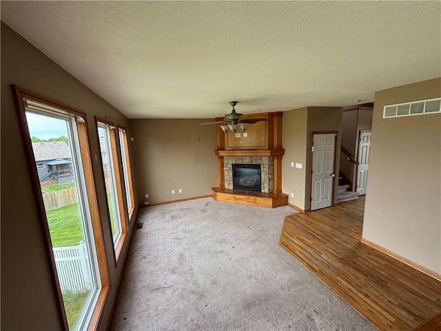 952 NW Maplewood Ct, Grain Valley, MO 64029 - unfurnished living room featuring ceiling fan, a textured ceiling, a fireplace, baseboards, and stairs