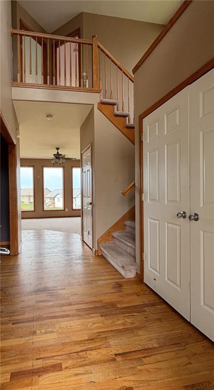 952 NW Maplewood Ct, Grain Valley, MO 64029 - foyer featuring light wood-style floors, stairs, ceiling fan, and a towering ceiling