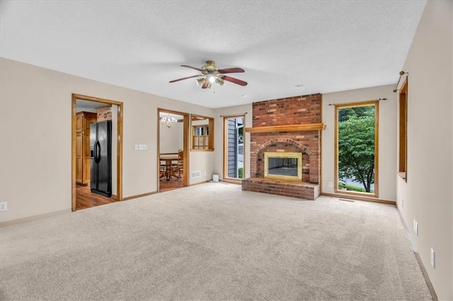 4506 NW Apache Dr, Riverside, MO 64150 - unfurnished living room with carpet floors, ceiling fan, a fireplace, a textured ceiling, and a chandelier