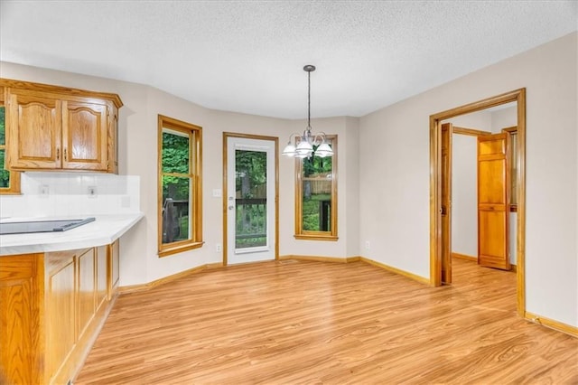 4506 NW Apache Dr, Riverside, MO 64150 - unfurnished dining area featuring healthy amount of natural light, light wood finished floors, a chandelier, baseboards, and a textured ceiling