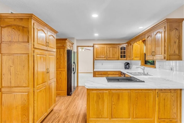 4506 NW Apache Dr, Riverside, MO 64150 - kitchen with a sink, black fridge with ice dispenser, a peninsula, cooktop, and light wood-style flooring