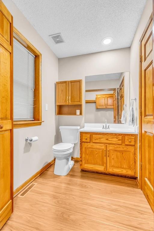 4506 NW Apache Dr, Riverside, MO 64150 - bathroom featuring toilet, a textured ceiling, wood finished floors, vanity, and baseboards