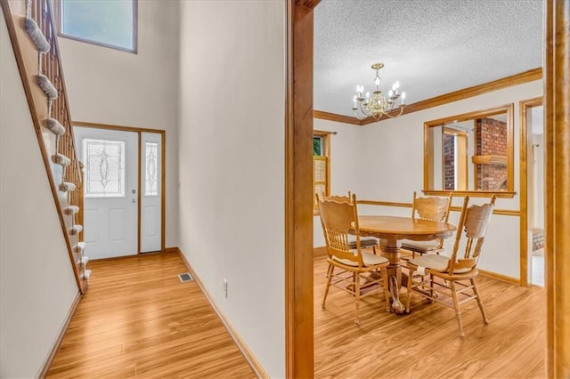 4506 NW Apache Dr, Riverside, MO 64150 - dining room featuring crown molding, a textured ceiling, light wood finished floors, a chandelier, and stairs