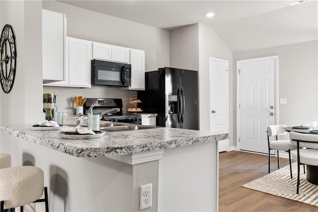 37838 W 208th Ter, Edgerton, KS 66021 - kitchen with black appliances, a peninsula, a kitchen bar, white cabinetry, and light countertops