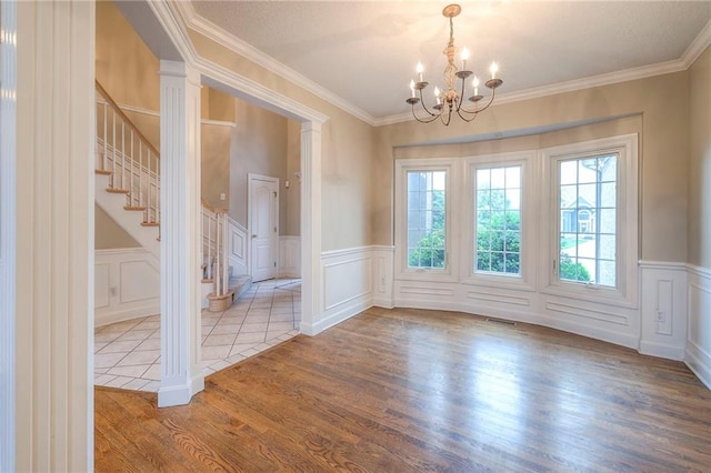 5706 NE Sapphire Pl, Lees Summit, MO 64064 - empty room featuring wood finished floors, a chandelier, stairs, a decorative wall, and ornamental molding