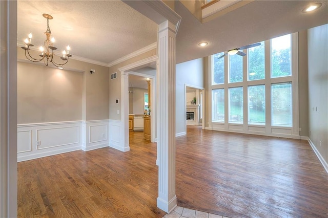 5706 NE Sapphire Pl, Lees Summit, MO 64064 - empty room featuring ceiling fan, wood finished floors, crown molding, a glass covered fireplace, and a chandelier
