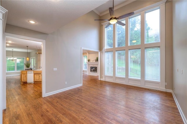 5706 NE Sapphire Pl, Lees Summit, MO 64064 - unfurnished living room featuring a glass covered fireplace, wood finished floors, baseboards, a chandelier, and ceiling fan