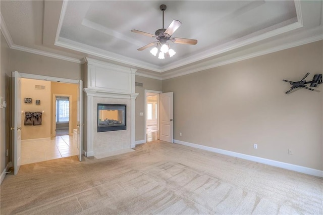 5706 NE Sapphire Pl, Lees Summit, MO 64064 - unfurnished living room with a tray ceiling, light colored carpet, ornamental molding, a ceiling fan, and a tile fireplace