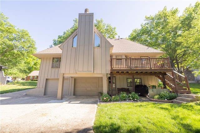 401 E 129th Ter, Kansas City, MO 64145 - view of front of house featuring board and batten siding, an attached garage, a wooden deck, and a front lawn