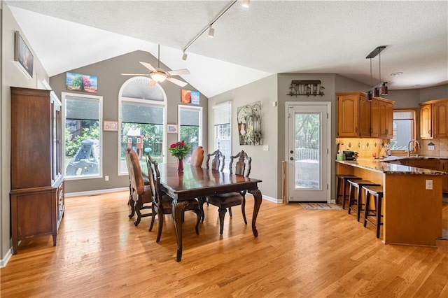11415 Oakview Dr, Lenexa, KS 66215 - dining space with light wood-type flooring, ceiling fan, plenty of natural light, vaulted ceiling, and a textured ceiling