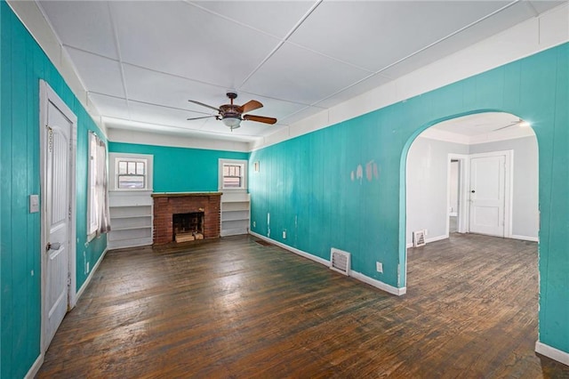 1409 N 24th St, Kansas City, KS 66102 - unfurnished living room featuring a ceiling fan, arched walkways, hardwood / wood-style flooring, and a fireplace