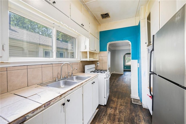 1409 N 24th St, Kansas City, KS 66102 - kitchen with freestanding refrigerator, gas range gas stove, a sink, dark wood-type flooring, and arched walkways