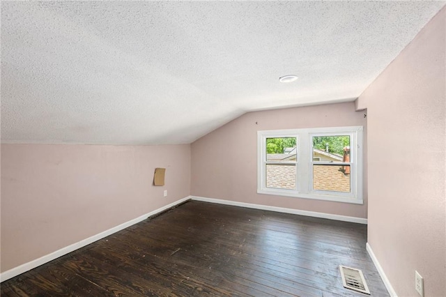 1409 N 24th St, Kansas City, KS 66102 - additional living space featuring a textured ceiling, hardwood / wood-style floors, lofted ceiling, and baseboards