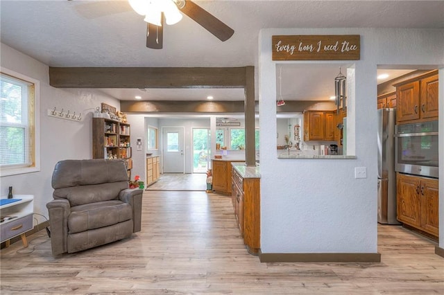 25801 E 317th Ter, Harrisonville, MO 64701 - kitchen featuring stainless steel appliances, ceiling fan, light wood finished floors, brown cabinets, and a textured wall
