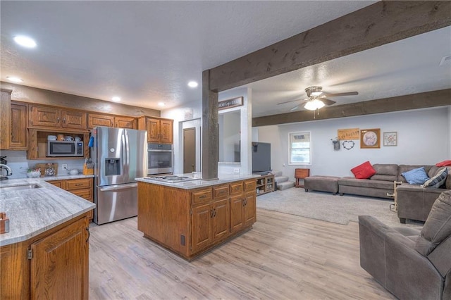 25801 E 317th Ter, Harrisonville, MO 64701 - kitchen featuring appliances with stainless steel finishes, open floor plan, light wood-style floors, brown cabinetry, and a ceiling fan