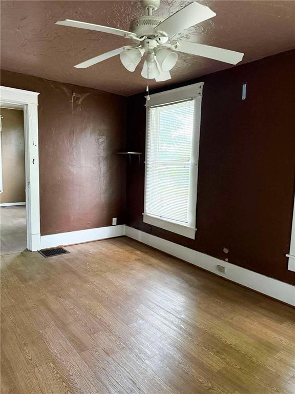 1202 Wall St, Galena, KS 66739 - empty room featuring ceiling fan, wood finished floors, baseboards, and a textured ceiling