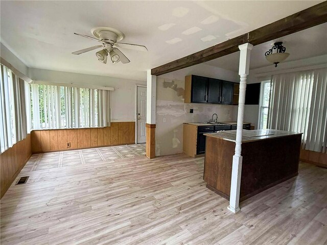 1202 Wall St, Galena, KS 66739 - kitchen featuring light wood-style flooring, ceiling fan, a sink, beamed ceiling, and wooden walls