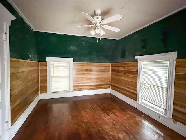 1202 Wall St, Galena, KS 66739 - unfurnished room featuring wooden walls, wood finished floors, plenty of natural light, a wainscoted wall, and a ceiling fan
