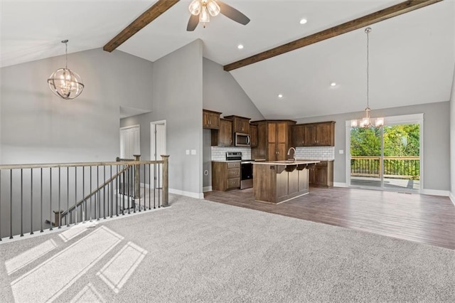 11207 207th St, Peculiar, MO 64078 - kitchen with open floor plan, a chandelier, appliances with stainless steel finishes, carpet, and high vaulted ceiling