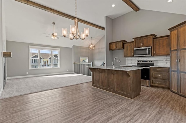 11207 207th St, Peculiar, MO 64078 - kitchen with appliances with stainless steel finishes, open floor plan, beamed ceiling, baseboards, and high vaulted ceiling