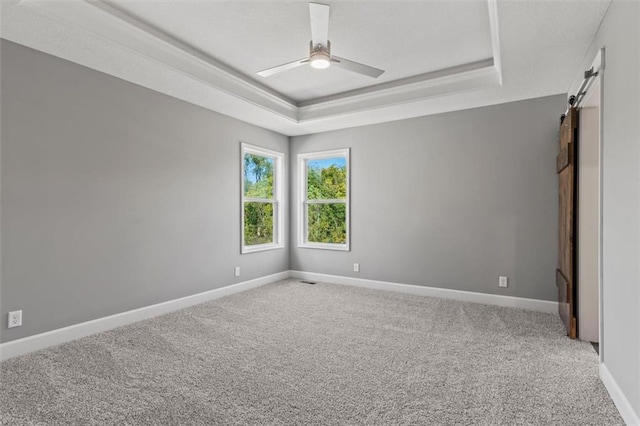 11207 207th St, Peculiar, MO 64078 - carpeted empty room featuring a barn door, a raised ceiling, ceiling fan, and baseboards