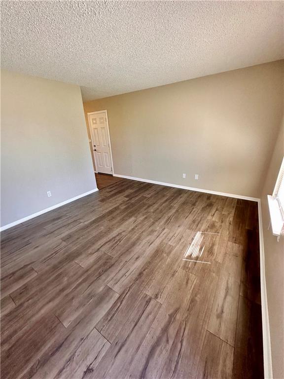 1710 Halsey Ave, Independence, KS 67301 - unfurnished room with dark wood-style floors, a textured ceiling, and baseboards