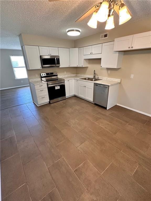 1710 Halsey Ave, Independence, KS 67301 - kitchen featuring appliances with stainless steel finishes, a sink, baseboards, a textured ceiling, and light countertops