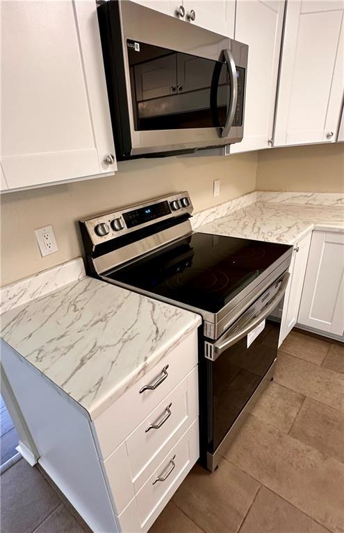 1710 Halsey Ave, Independence, KS 67301 - kitchen featuring stainless steel appliances, white cabinets, and light stone countertops