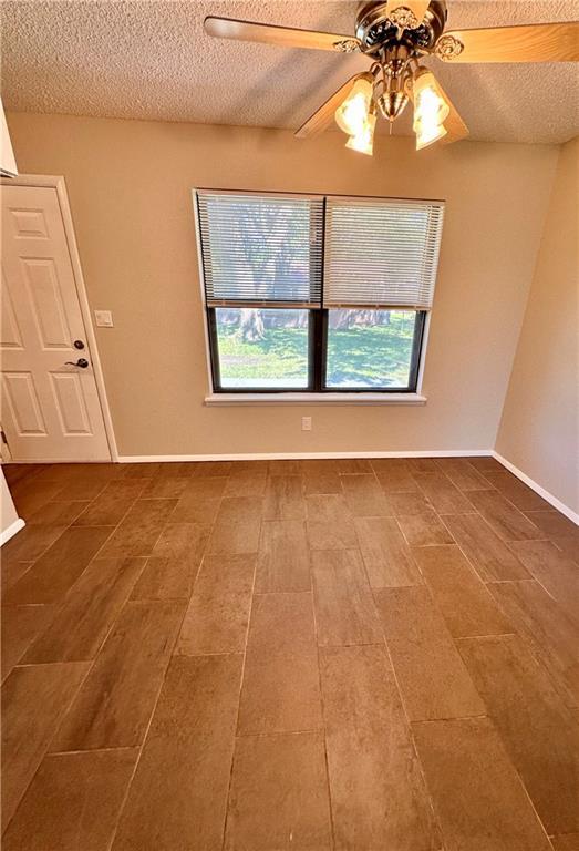 1710 Halsey Ave, Independence, KS 67301 - empty room with a textured ceiling, plenty of natural light, a ceiling fan, and baseboards