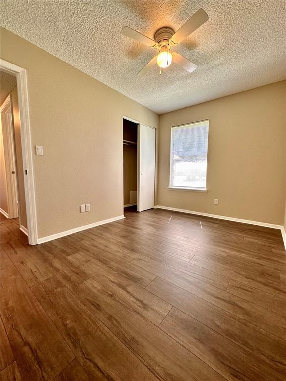 1710 Halsey Ave, Independence, KS 67301 - unfurnished bedroom featuring a textured ceiling, a closet, dark wood-style floors, ceiling fan, and baseboards