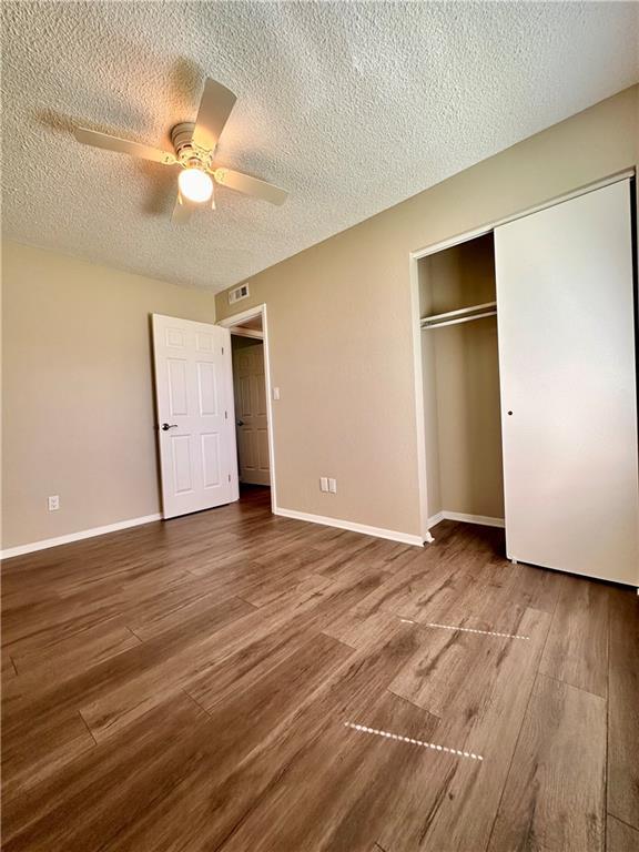 1710 Halsey Ave, Independence, KS 67301 - unfurnished bedroom featuring a textured ceiling, a closet, wood finished floors, a ceiling fan, and baseboards