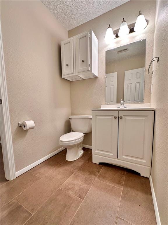 1710 Halsey Ave, Independence, KS 67301 - bathroom featuring toilet, vanity, a textured ceiling, tile patterned flooring, and baseboards