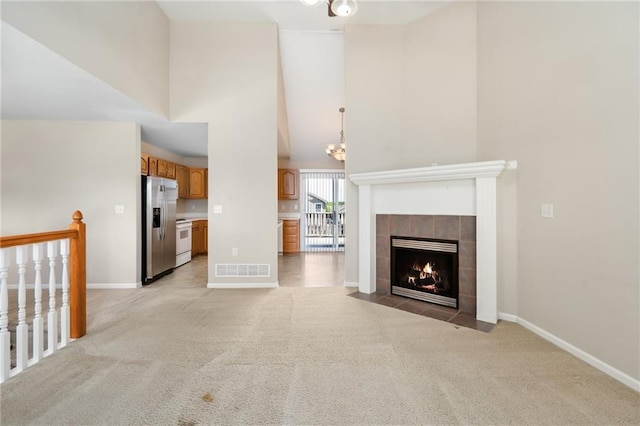 706 E 15th St E, Eudora, KS 66025 - unfurnished living room featuring a high ceiling, light carpet, baseboards, a fireplace, and a chandelier