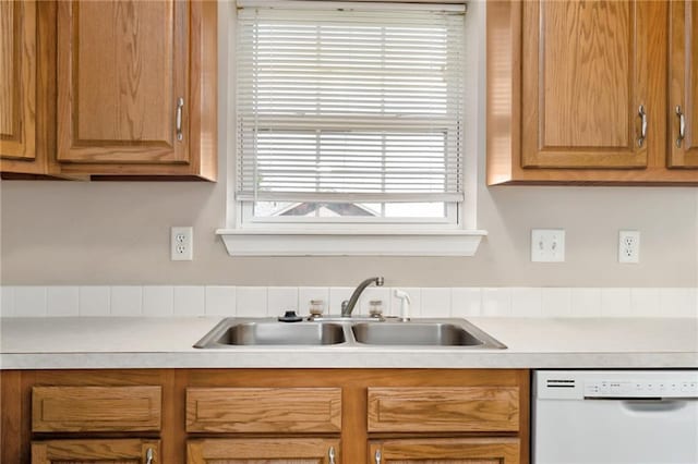 706 E 15th St E, Eudora, KS 66025 - kitchen with white dishwasher, a sink, light countertops, and brown cabinets