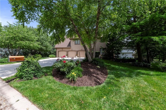 15141 Windsor Cir, Leawood, KS 66224 - view of property hidden behind natural elements with driveway, an attached garage, stucco siding, and a front yard