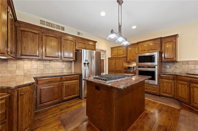 15141 Windsor Cir, Leawood, KS 66224 - kitchen featuring stainless steel appliances, a kitchen island, dark wood-style floors, decorative backsplash, and brown cabinetry