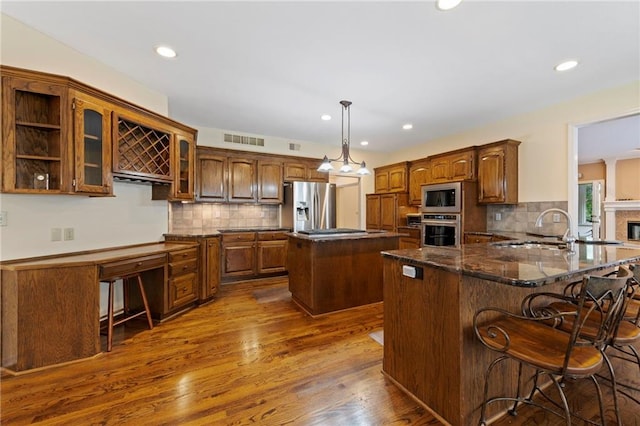 15141 Windsor Cir, Leawood, KS 66224 - kitchen with appliances with stainless steel finishes, a center island, tasteful backsplash, dark wood finished floors, and a kitchen breakfast bar