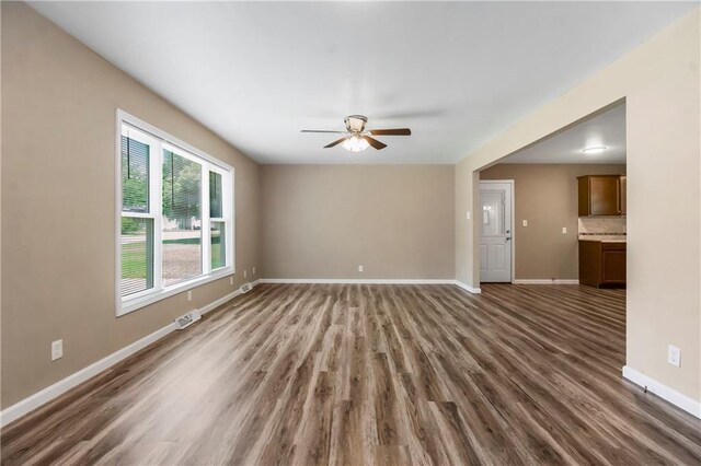 707 N Delaware St, Butler, MO 64730 - unfurnished living room with ceiling fan, dark wood-style floors, and baseboards