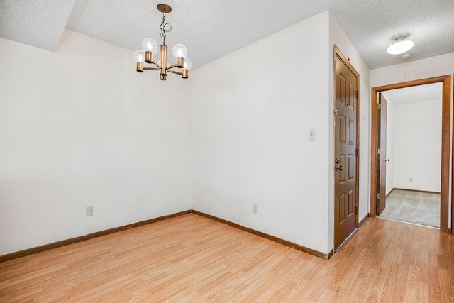 1339 Westbrooke St, Lawrence, KS 66049 - unfurnished room with light wood finished floors, baseboards, a chandelier, and a textured ceiling
